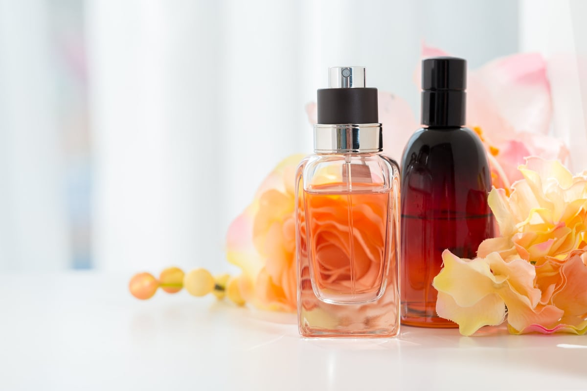 Dos frascos de perfume junto a flores frescas en luz suave